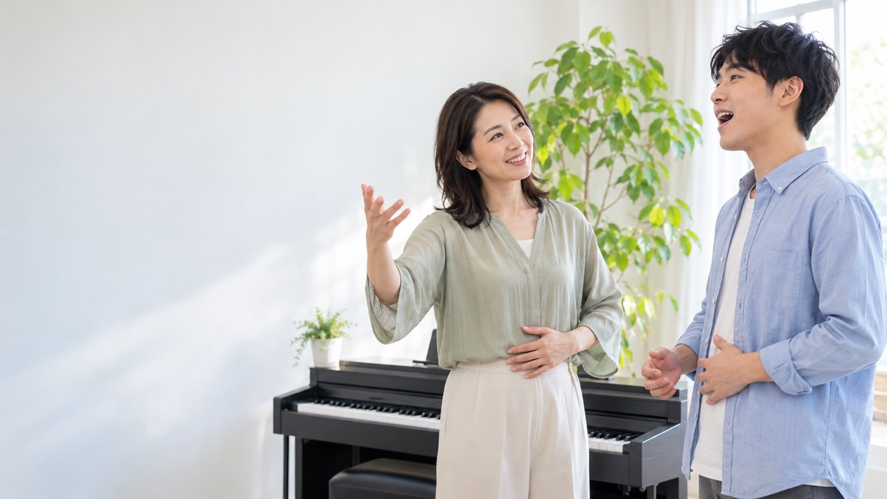 ボイトレ教室で、先生がピアノの横で生徒に発声を教える様子